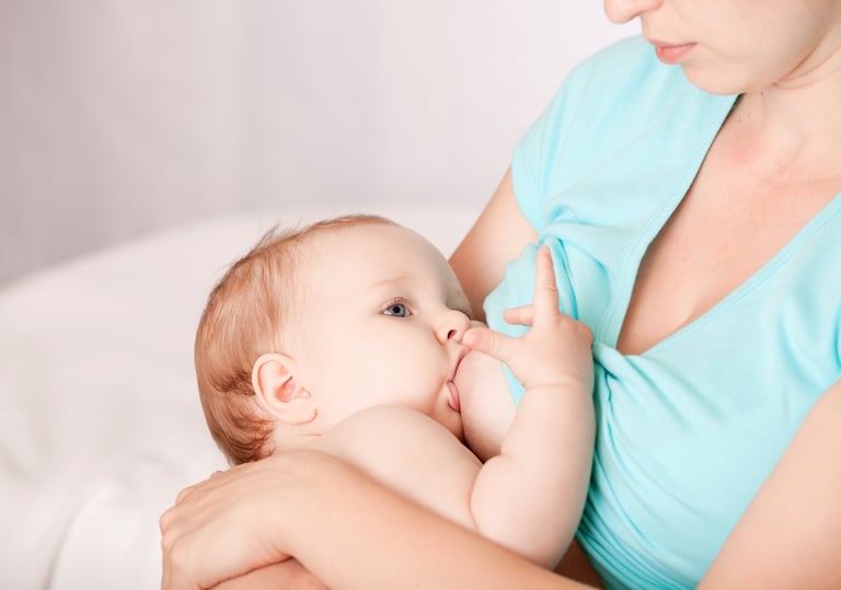 a woman breastfeeding a baby in a blue dress