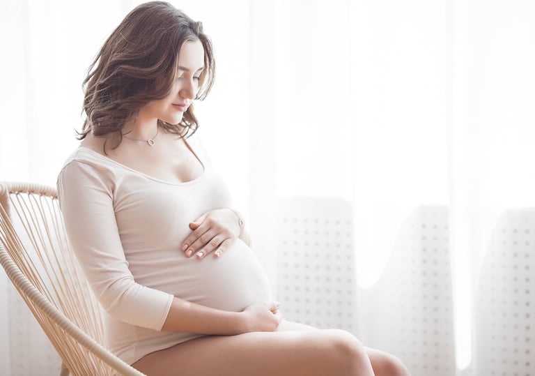 a pregnant woman sitting in a chair holding her belly