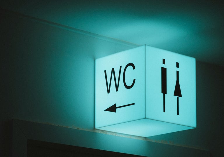 Illuminated blue WC restroom sign with male and female icons and a directional arrow.