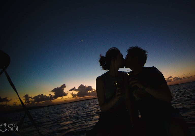 The photo shows a couple kissing on a sunset boat tour.