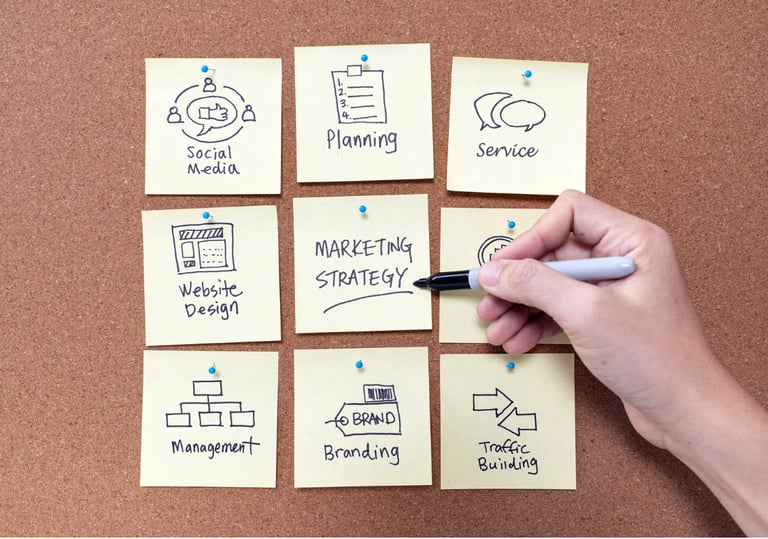 a person's hand holding a pen and writing on sticky notes