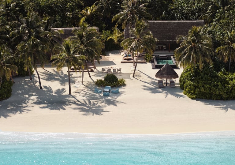 a beach with a beach chair and palm trees, One and Only Reethi Rah