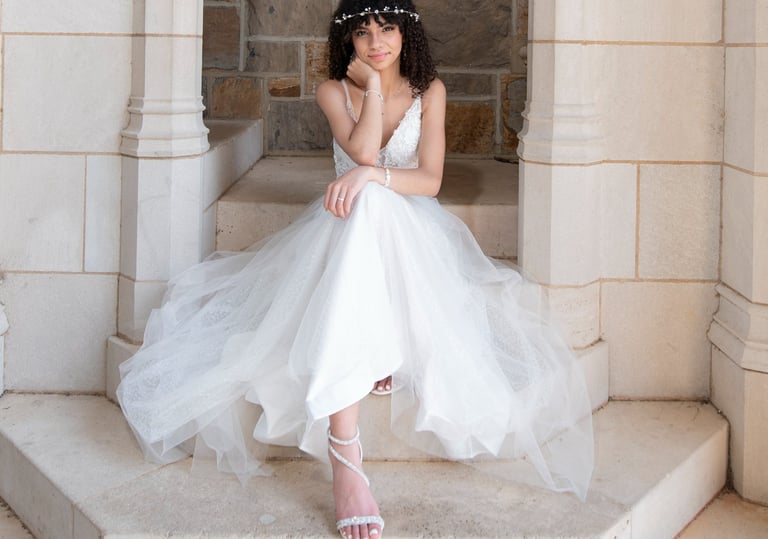 quinceanera in a white dress sitting on a stone stepstone