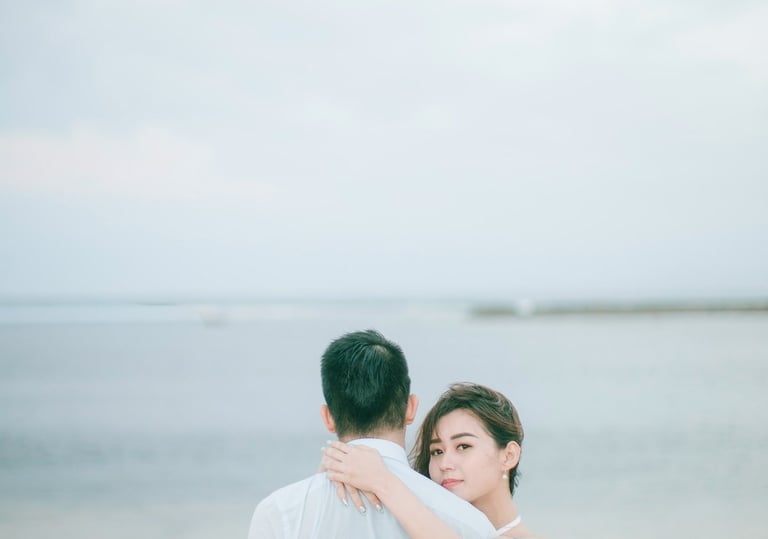 Romantic couple embracing by the ocean at Sofitel Bali Nusa Dua Beach Resort.