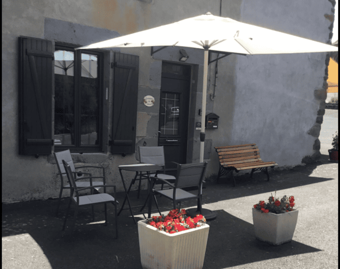 Entrée du gîte avec la table, les chaises sous un parasol