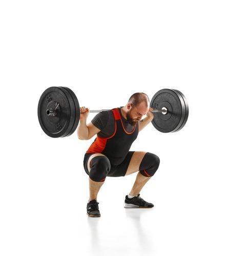 Professional powerlifter performing a heavy barbell back squat exercise on a white background.