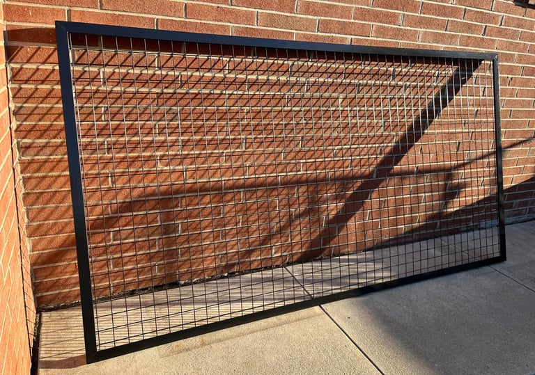 Custom welded wire mesh protective screen leaning against a brick wall