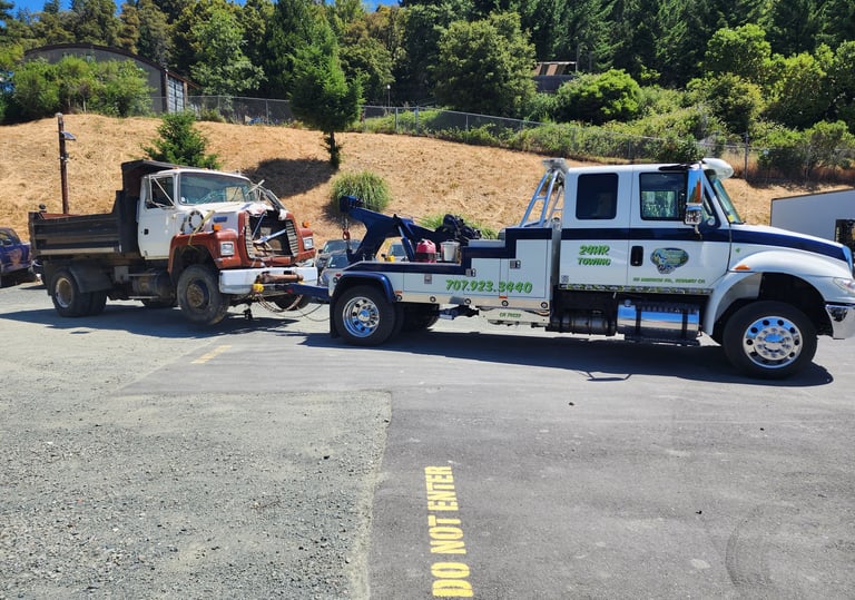 Redwood Towing medium duty tow truck towing a large dump truck.