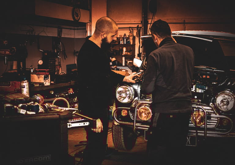 two men working on a mini cooper  in  garage ; deux hommes travaille sur le moteur d'une mini cooper
