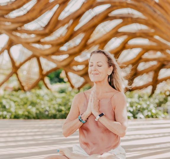 retreat in Mexico - a woman in a pink tank top and white shorts sitting on a wooden floor