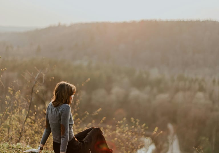 a woman sitting on a hill with a dog