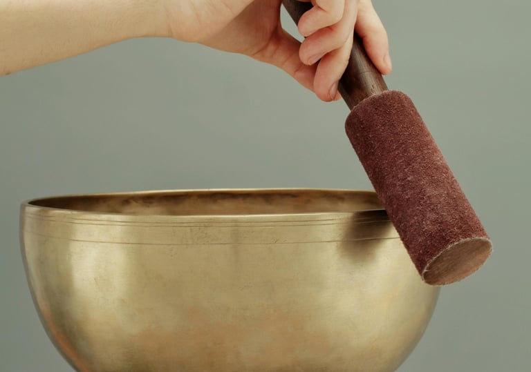 a person holding a singing bowl with a hand holding a small object