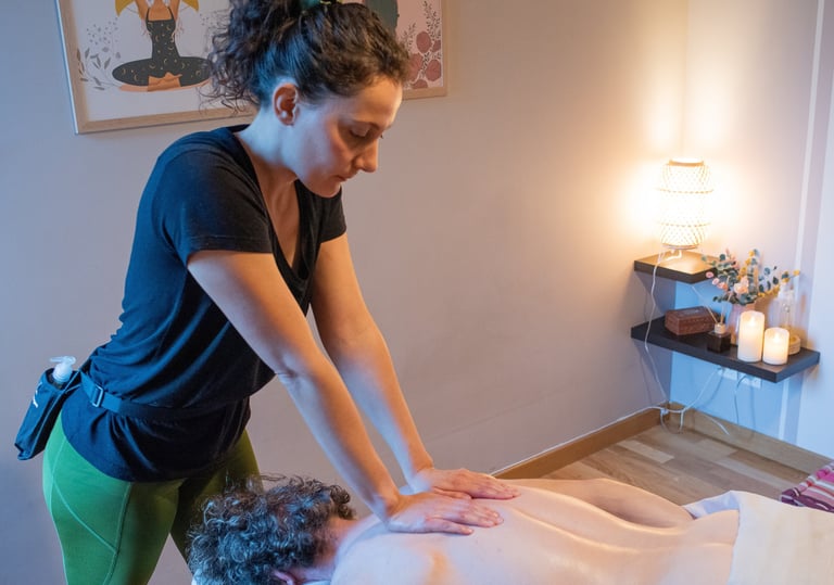 Masseuse bras tendus qui masse le dos d'un client avec bougies et décoration dans la pièce