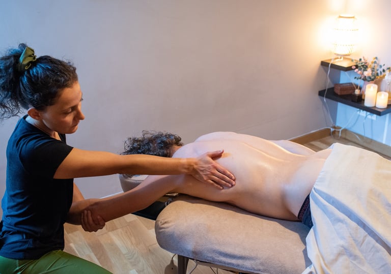 Masseuse accroupie qui masse le long du grand dorsal en tirant le bras du client