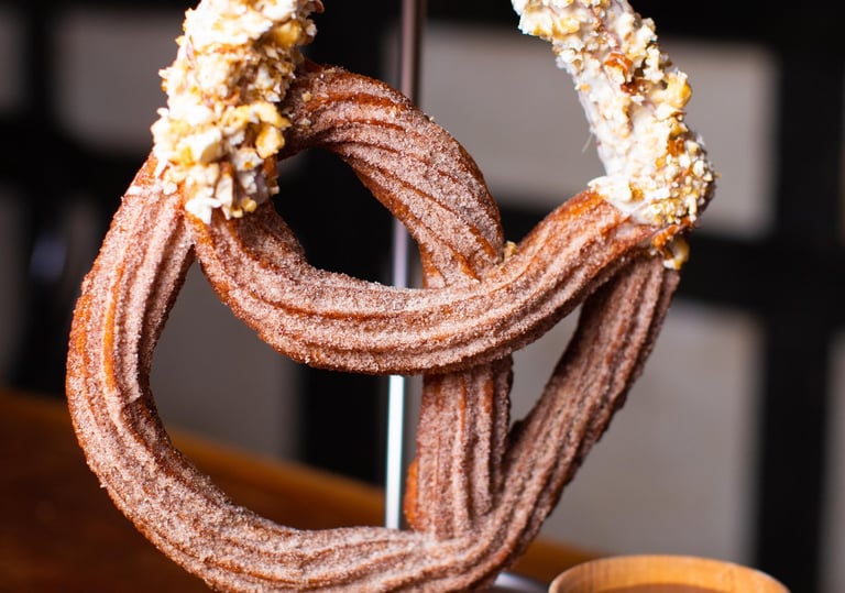 a huge churro pretzel hanging from a stand like a pretzel