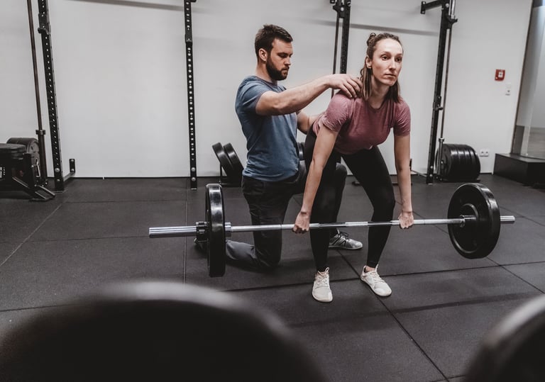 Ein Trainer korrigiert die Bewegungsausführung beim Hanteltraining