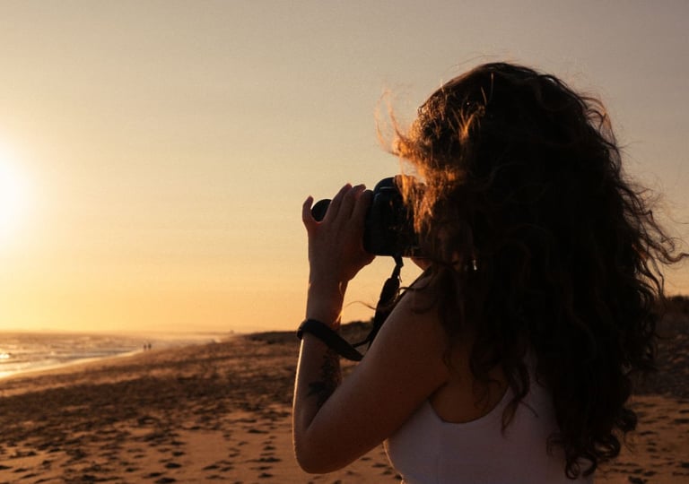 a woman taking a picture of a sunset