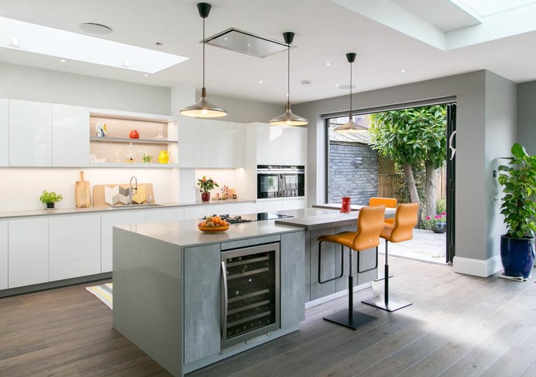 an open plan modern kitchen with orange bar stools, grey concrete  island cabinets, dark wood floor