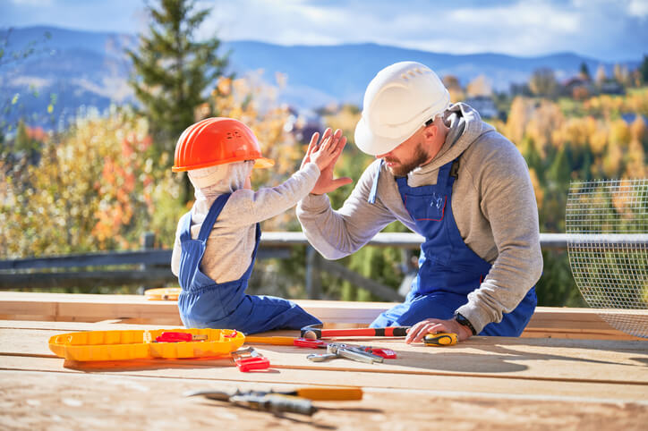 Un père et son fils en tenu de travail se tapant la main