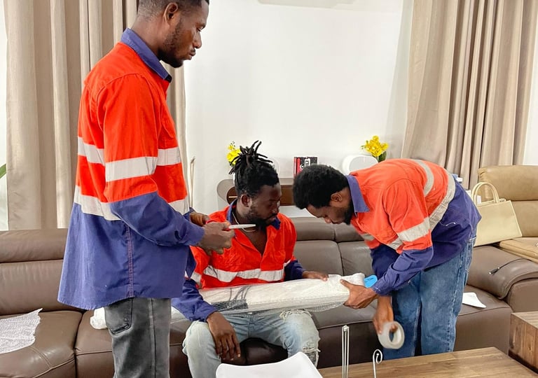 Three professional movers in orange high-visibility shirts with reflective stripes collaborate to wr