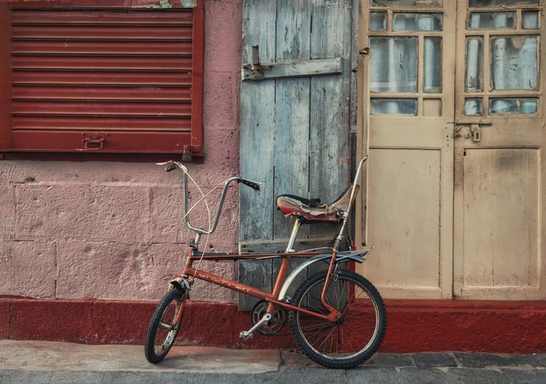 An old bicycle leaning against a weathered wooden door and wall with contrasting colors in Port Louis, Mauritius