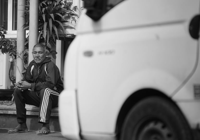 A man sits on a step, resting and observing the street in Rodrigues