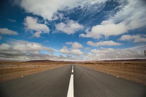 Empty desert road with white lines disappearing into the distance on Ultimate Sahara road trip