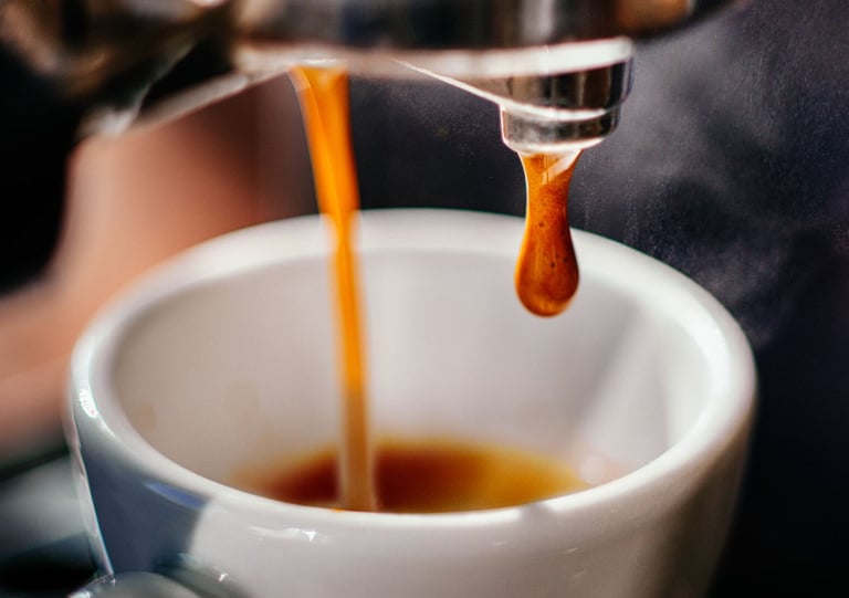 a person is pouring a cup of coffee into a cup