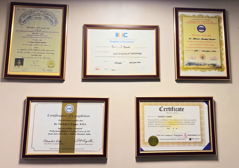 Professional dental certificates and implantology diplomas framed on a clinic wall for Dr. Sandesh Kumar.