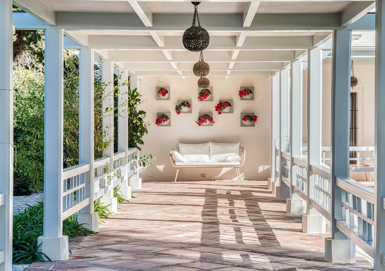 Shaded pergola walkway with lanterns and floral wall detail
