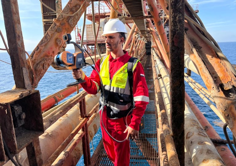 Engineer using a handheld ZEB Horizon SLAM laser scanner for 3D mapping on an offshore oil platform.