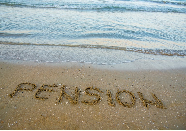 Arena y mar con la palabra pensión escrita en la arena
