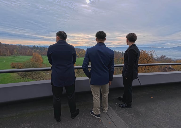 Three men standing on a balcony overlooking a landscape, symbolizing long-term vision and strategic 