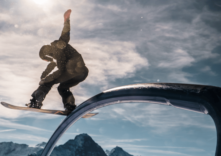 a snowboarder is riding a rail rail in the mountains