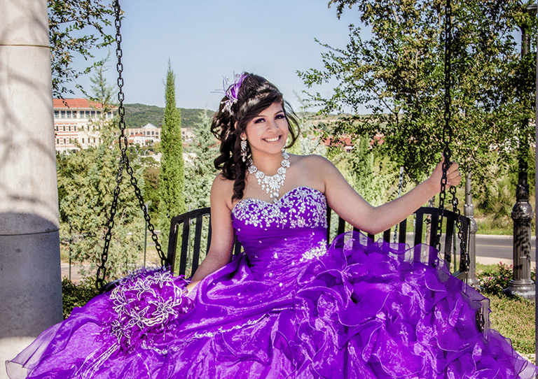 a woman in a purple quinceanera dress sitting on a bench