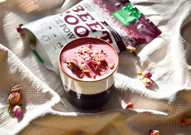 a cup of pink latte with a bag of beetroot powder