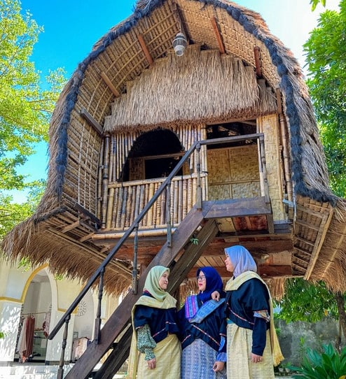 a group of women in traditional dress clothes standing in front of a thatched house in sade village