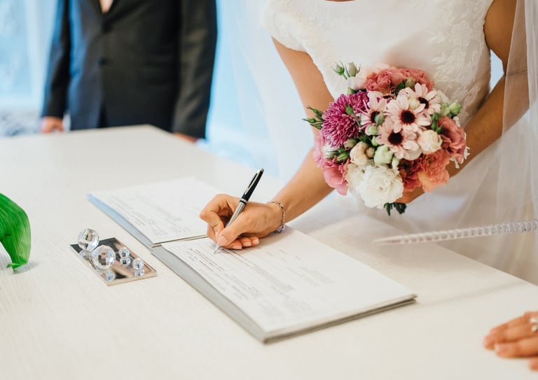 Bride signing the wedding register with bouquet—enquire to book your Glasgow wedding videographer.