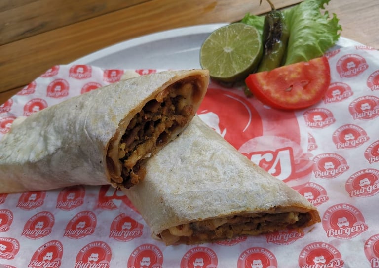 Un burrito de bistec al estilo mexicano, cortado en rebanadas y servido con lima, jalapeño y tomate 