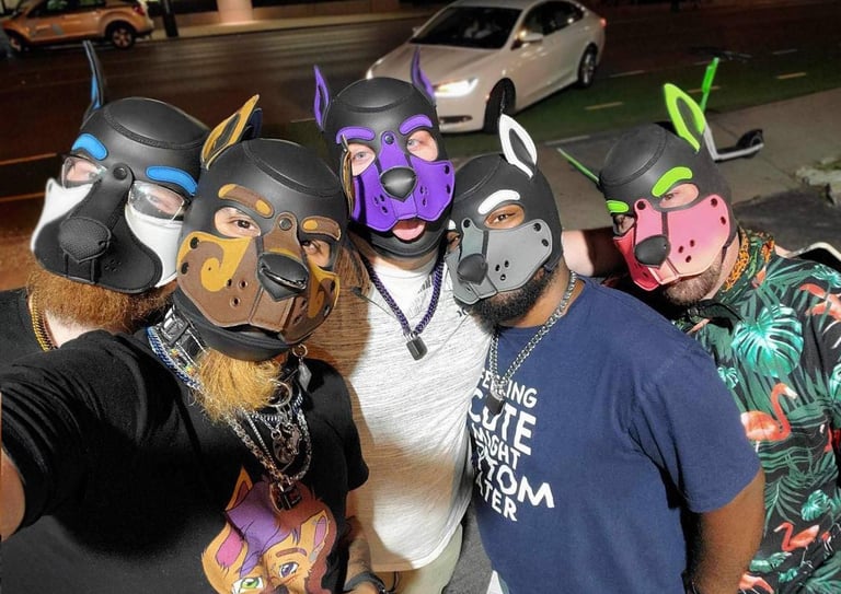 A group of men in pup masks posing on the street at night.