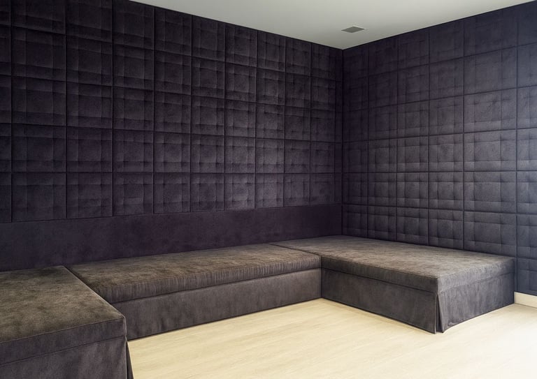 Modern corner design with custom upholstered wall panels and matching L-shaped seating in dark fabric by Solo Home Decor.