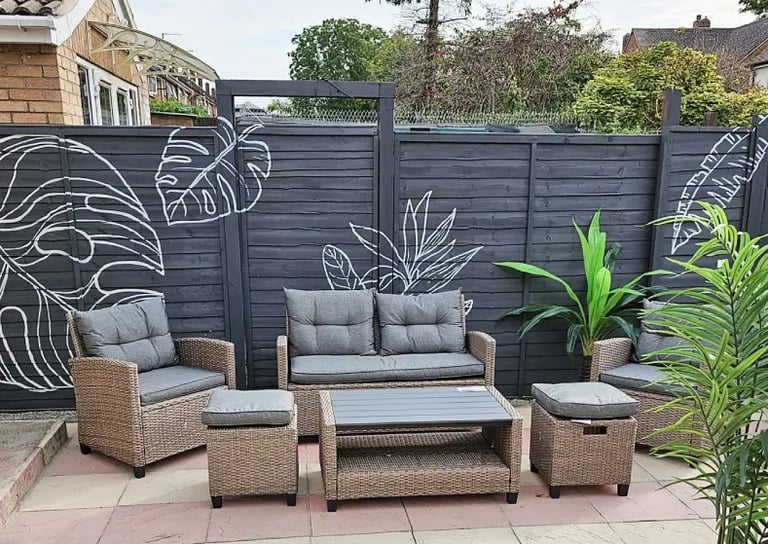 Yard with grey fence featuring graphic plant mural, modern seating and plants.