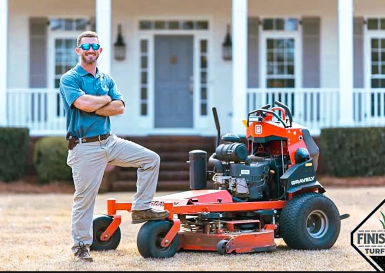 Finish Line Turf and Pest Owner Brandon Morris Standing In Front of house and eqiment. 