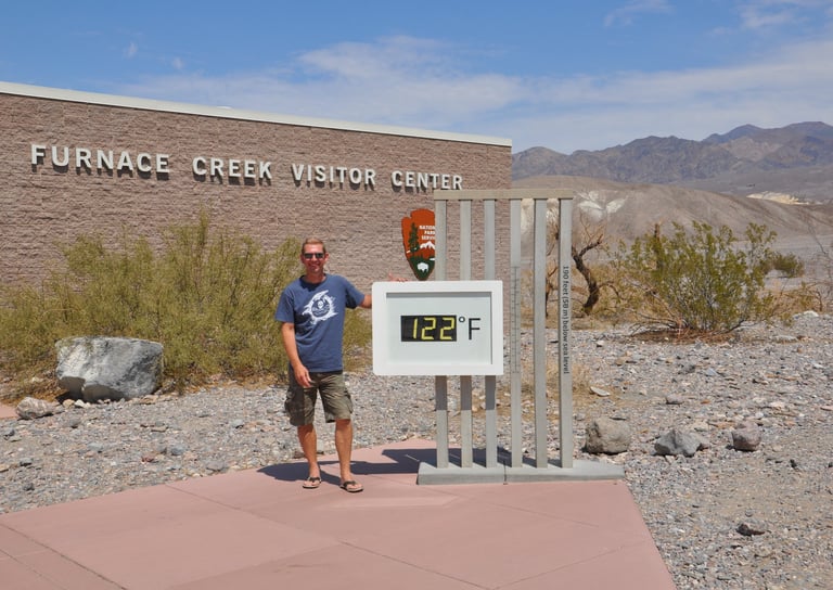a man standing in front of a sign that says furnace creek, death valley
