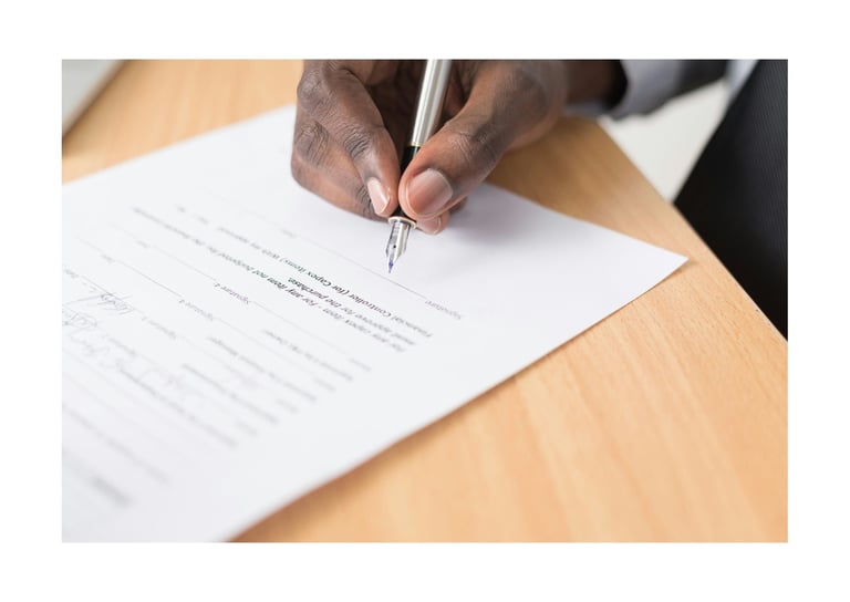 A man's hand holding a fountain pen over an employment contract