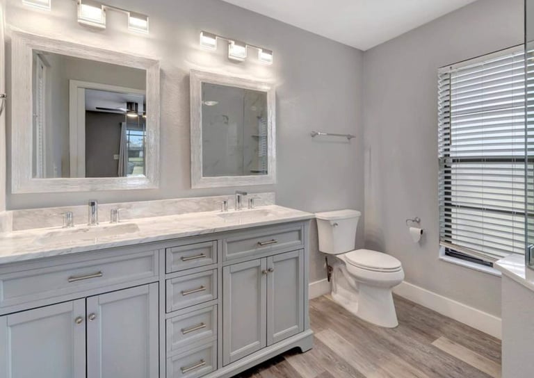 Bathroom remodel with a double vanity, framed mirrors, overhead lighting, and a toilet.