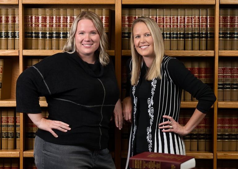 two women standing in front of a bookcase in an office