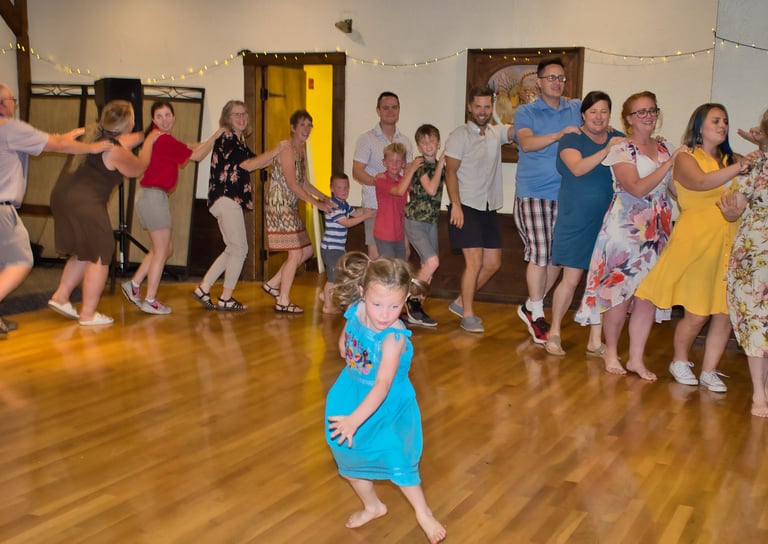 a young girl in a blue dress dancing in front of a group of people