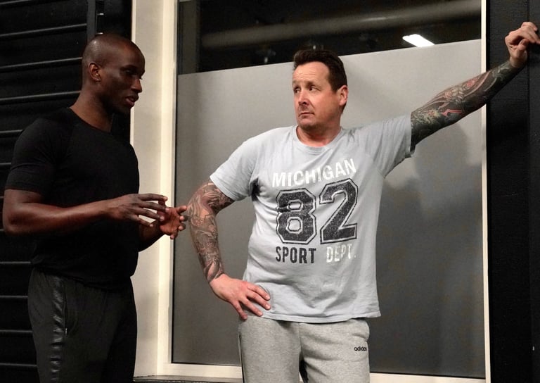 A personal fitness trainer talks to a client during a gym workout session.