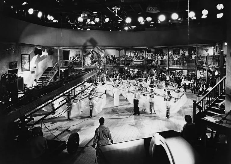 Berkeley on a crane boom filming white‑skirted female dancers from above in a classic overhead shot.
